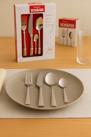 Schäfer Besteckset Metallic Silber auf gedecktem Esstisch mit grauem Teller, Serviette und Verpackung im Hintergrund